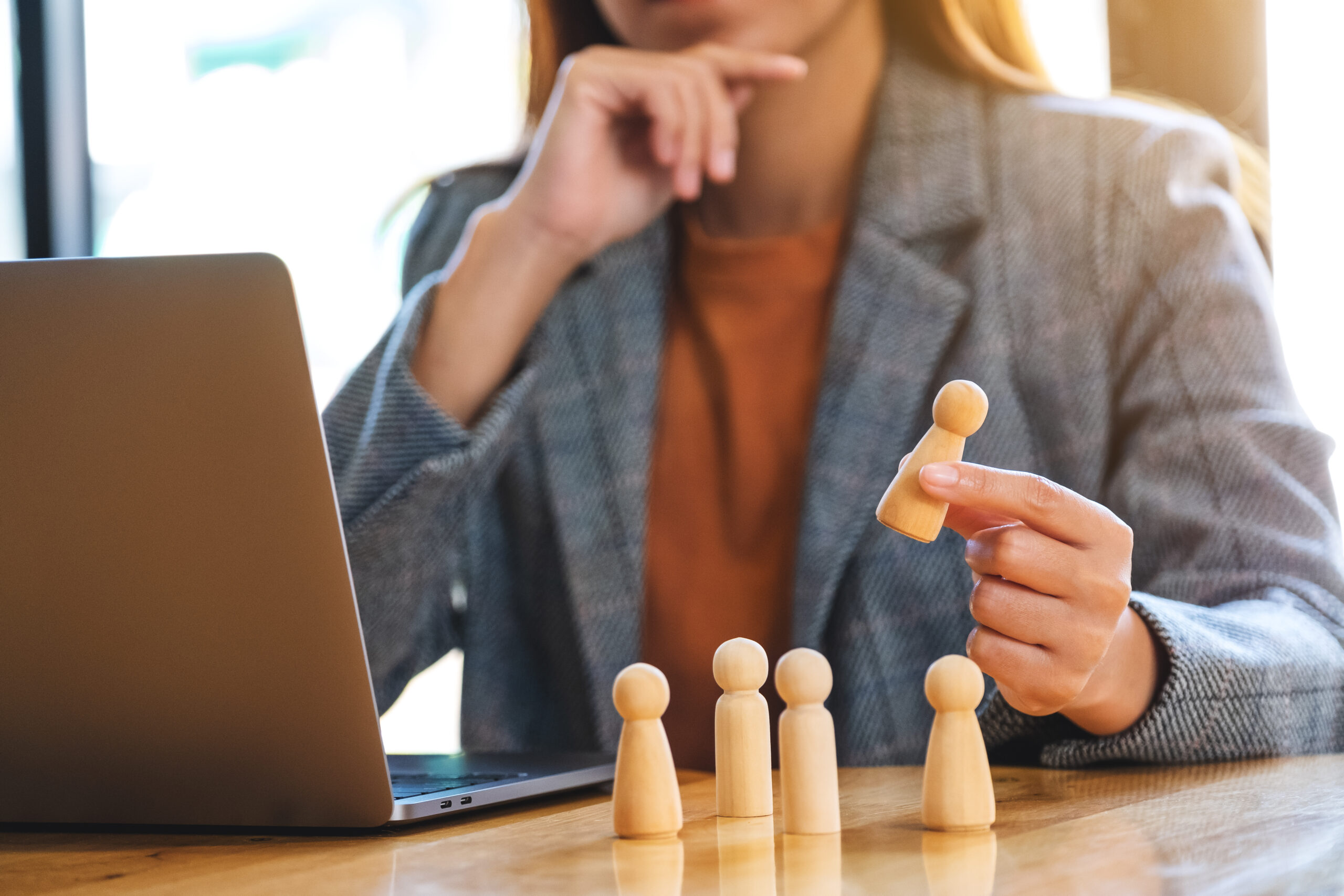 Businesswoman leader holding and choosing wooden people from a g